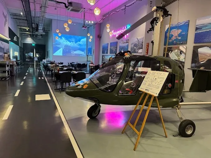 Image an aviation-themed cafe located inside a real aircraft hangar in Singapore's Seletar Aerospace View